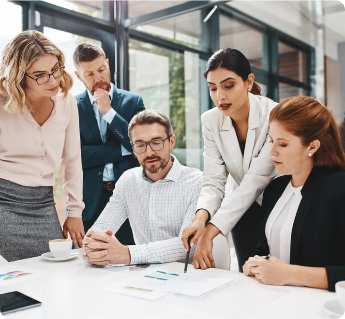 Group of business professionals collaborating on financial documents in a modern office, representing teamwork and expertise in accounting and financial management.